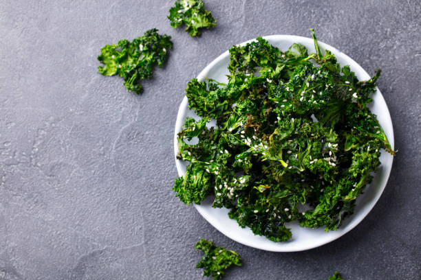 istock Kale chips, healthy snack on a plate. Grey background. Close up. Copy space. 1214754263