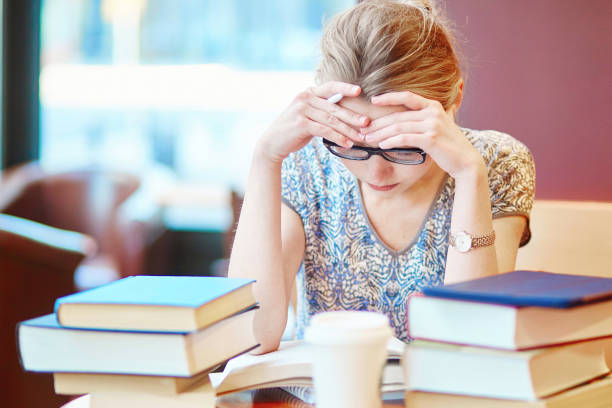 istock Exhausted student with books and papers, studying at home 1214754680