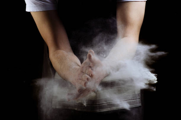 istock Chef hand clap and white flour on dark background 1214754791