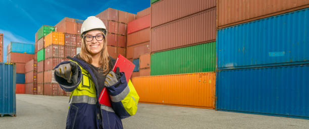 istock smiling port worker points her finger at the viewer in the background container 1214756627