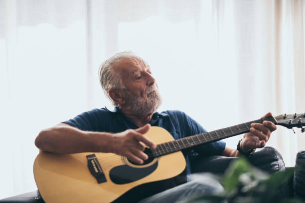 el anciano y su guitarra en la casa - plucking an instrument fotografías e imágenes de stock