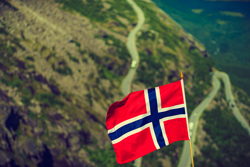 Norwegian flag and Trolls Path Trollstigen winding scenic mountain road in Norway Europe. National tourist route.