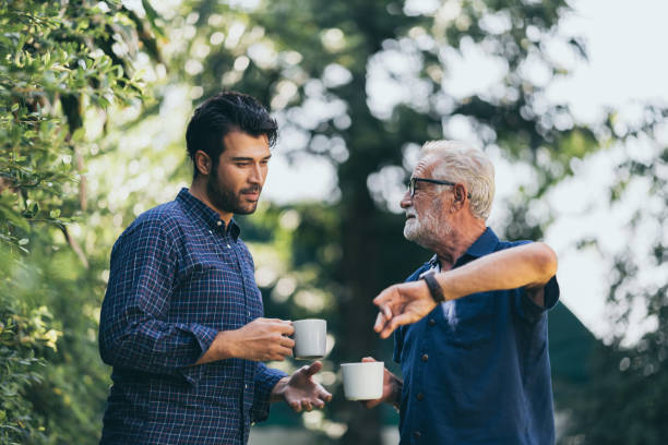 istock Father-son bonding. Cheerful young man drinking coffee together with him 1214758659