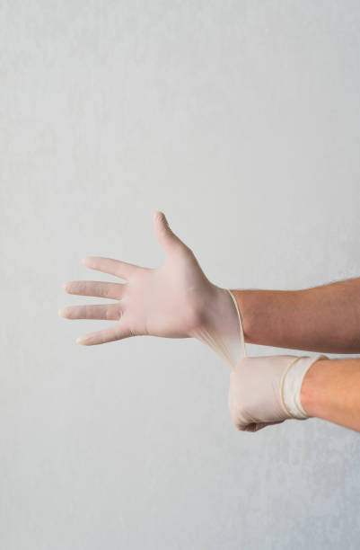 istock The concept of protection against coronavirus. Person pulls on white gloves before going outside during the Covid-19 epidemic. Safe protection against the cold and flu virus 1214759408