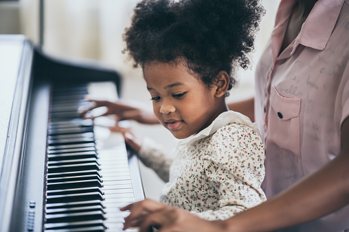 American African young pianist, teacher teaching girl kid student to play piano, Art of music education concept