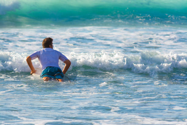 Surfer paddling to the lineup on a sunny day. Sardinia, Italy