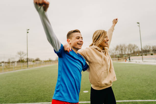 Photo of cheerful mother and son on a soccer field