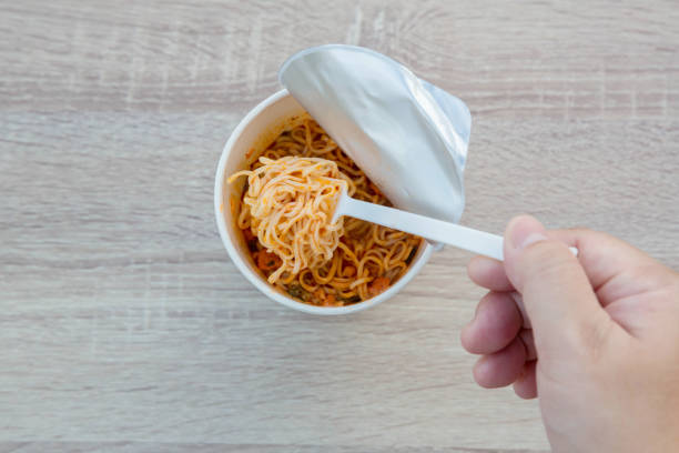 istock Hot noodle Cup. Noodle cup Ready made. Eating Instant Noodles with a Plastic Fork. Junk food Instant noodles are eating the popular food. 1214761021