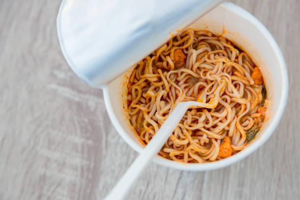 istock Hot noodle Cup. Noodle cup Ready made. Eating Instant Noodles with a Plastic Fork. Junk food Instant noodles are eating the popular food. 1214761040