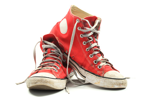 Old and dirty red canvas sneakers, isolated over white