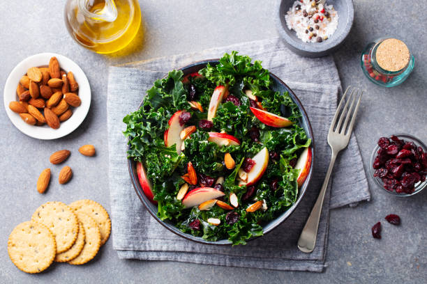 Kale salad with apples, cranberry and nuts. Grey background. Top view.