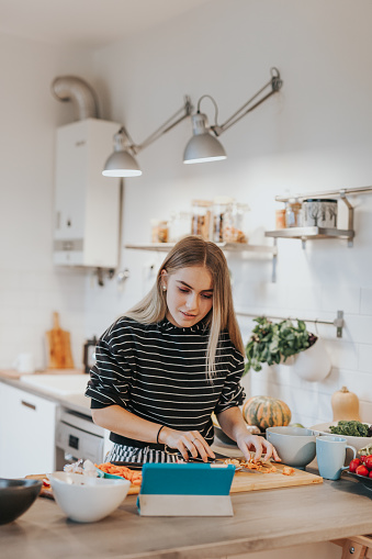 Photo series of two female teenage vegans learning to cook while watching tutorials in internet.