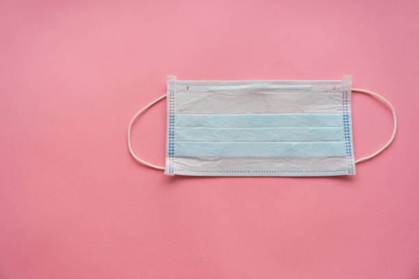 istock disposable medical mask on a pink background. 1214762872
