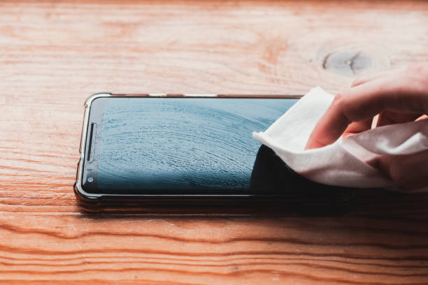 istock Cleaning mobile phone screen with disinfecting wet wipes for clean smartphone preventive wiping for COVID-19 Coronavirus outbreak contamination prevention. 1214763082