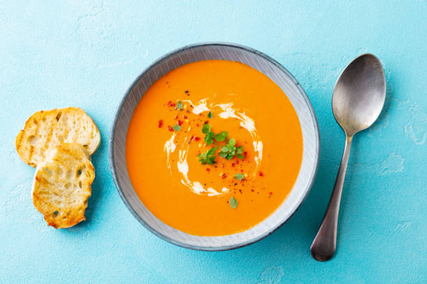 istock Pumpkin soup with fresh herbs in a bowl. Blue background. Top view. 1214763364