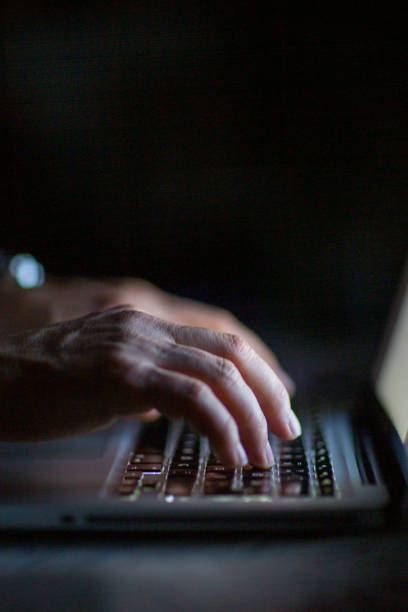 Close up of hands typing on laptop. Night work concept.