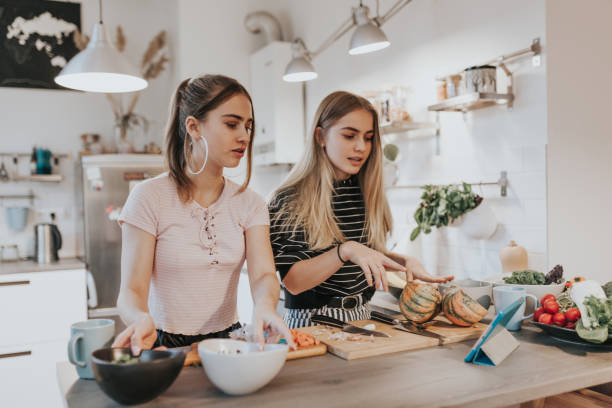 istock Two female teenagers cook dinner while having a video call conversation 1214764502