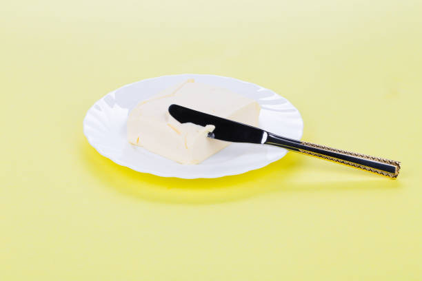istock Piece of butter on a white plate and a table knife. 1214766230