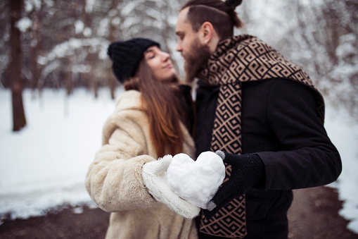 Loving couple holds a heart-shaped snowball