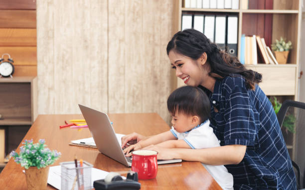 istock Asian business lady working on computer while her daughter 1214767973