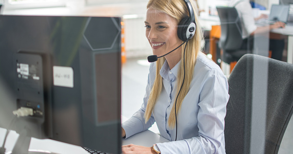 Helpline operator woman with headphones in call centre