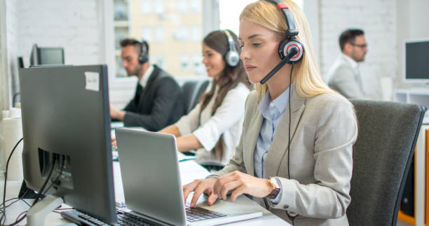 istock Female telephone worker in headset working on laptop in office 1214768744