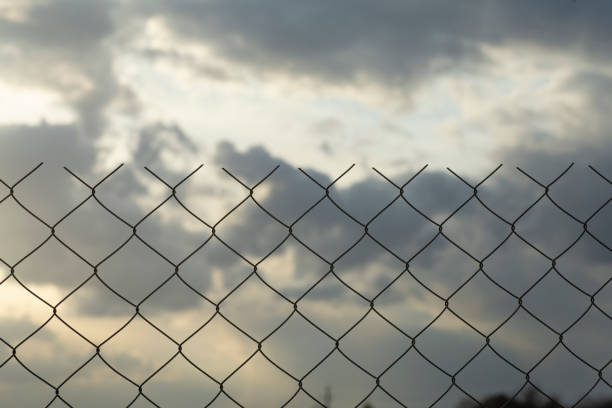 istock Restricted area concept. A metal mesh fence enclosing a restricted area (quarantine, prison, production area) 1214768939