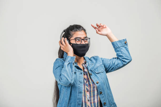 une adolescente avec le masque appréciant la musique tout en quarantaine pendant la pandémie de covid-19 - indian girls audio photos et images de collection