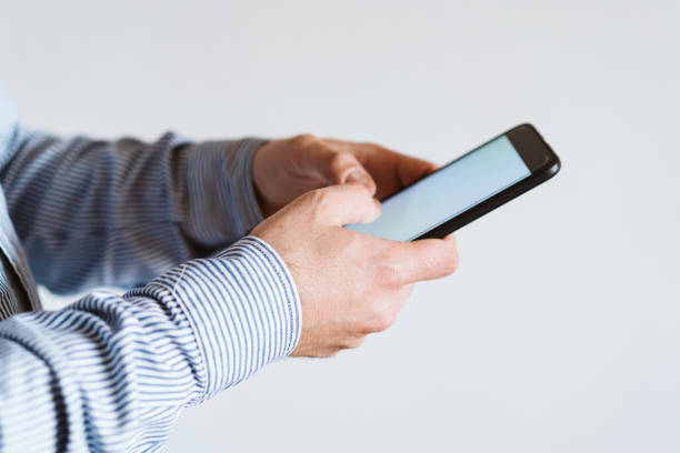 istock close up view of a man using mobile phone indoors. Technology concept 1214772810