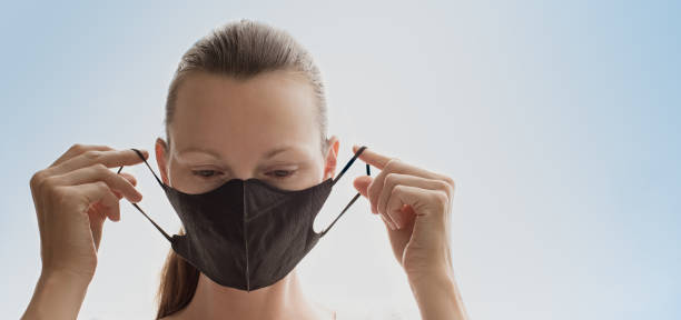 istock Woman putting on protective face mask 1214773366