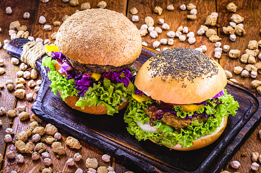 homemade vegan burger, with vegetables and various grains, on rustic wooden background. Healthy and vegetarian life concept. meatless snack, based on soy, chickpeas, corn and proteins.