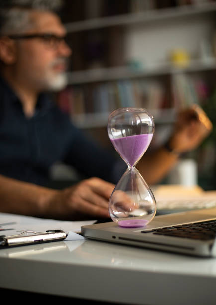 istock Business concepts with businessman holding hourglass with graph chart on computer laptop 1214776228