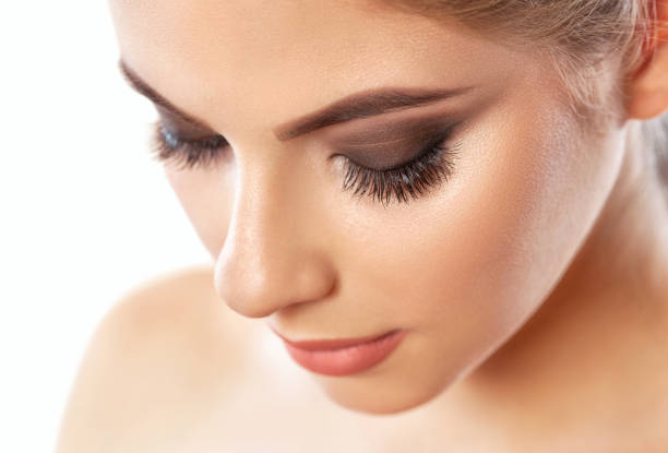 Beautiful woman with long eyelashes, beautiful make-up and thick eyebrows. Beautiful grey eyes close up. Professional makeup and cosmetology skin care.