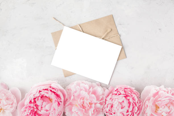istock Blank greeting card and envelope with pink peony flowers on concrete background. Wedding invitation. Flat lay. Mock up 1214779427