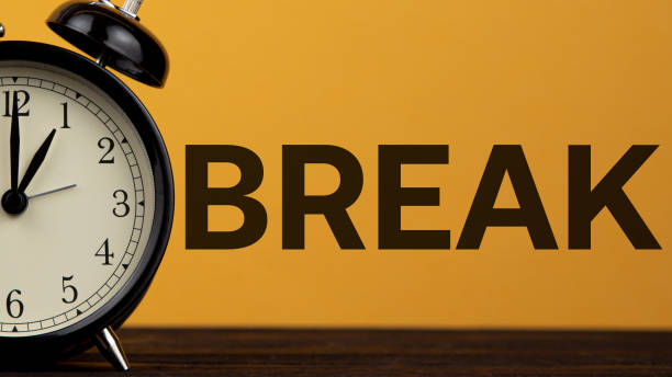 istock break, lunch time, alarm clock on a yellow background 1214779765