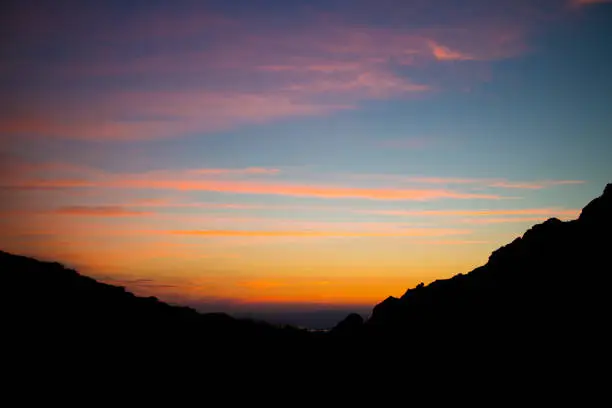 Photo of Bright pink-orange sunset sky on a black silhouette of mountains