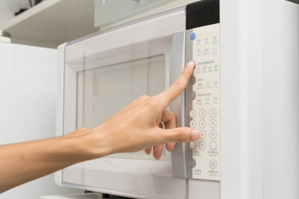 istock Male hand using a microwave oven in the kitchen 1214783540
