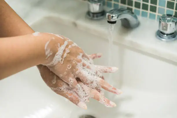 Photo of Young woman washing her hands with antibacterial disinfectant soap for prevention of coronavirus and other pandemic and epidemic diseases