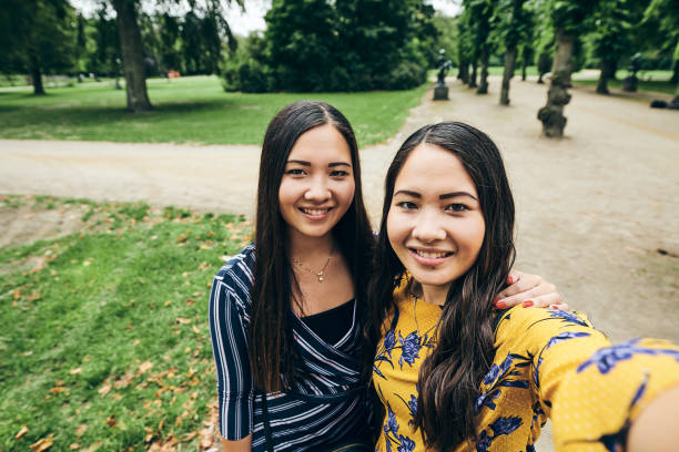istock Ethnic women talking selfie on park alley 1214784804