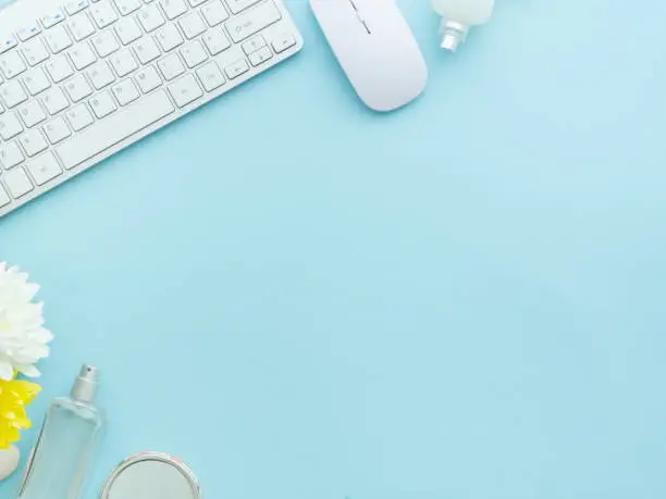 Photo of Freelancer woman blogger workplace, working space with laptop and perfume cosmetics bottles isolated on light blue table background