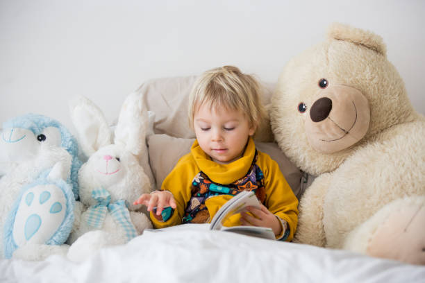 istock Beautiful child, toddler boy, reading book and playing with it, creative knowledge shot with book 1214789899