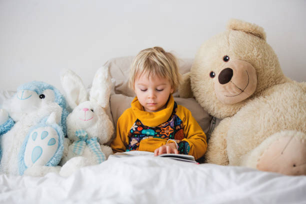 istock Beautiful child, toddler boy, reading book and playing with it, creative knowledge shot with book 1214790572