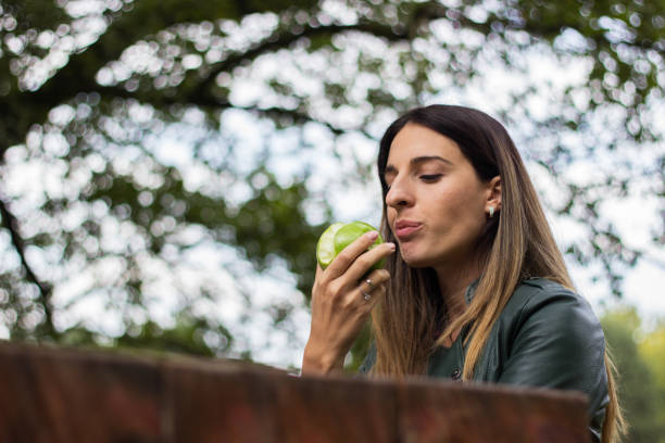 istock Cheerful young woman eating an apple 1214791481
