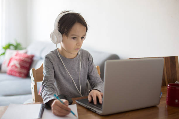 istock School child, sitting at the table with laptop, writing school tasks while homeschooling 1214793193