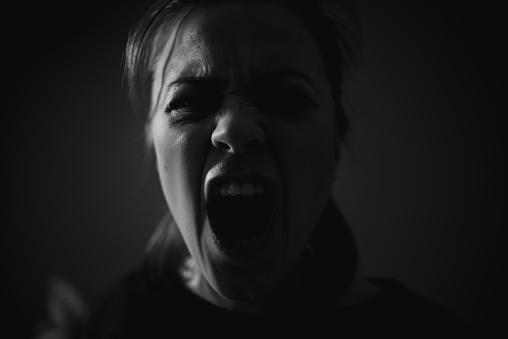 Young woman screams in the darkness.