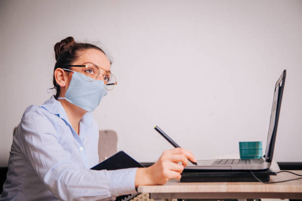 istock Woman with a mask on her working from home 1214797429