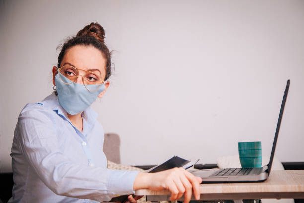 istock Woman with a mask on her working from home 1214800189