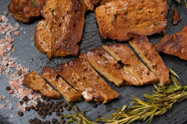 Roasted seitan steaks Roasted seitan steaks with herbs and spices on slate plate meat substitute stock pictures, royalty-free photos & images