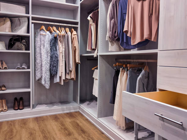walk in closet with clothes hanging and shoes on shelving A well stocked walk in closet with all clothing and shoes organized within wardrobe stock pictures, royalty-free photos & images