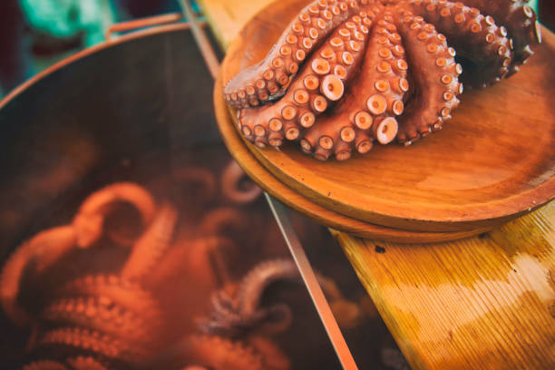 istock Galician octopus cooked on a wooden plate while more octopus is cooked in a metal pot. Typical cuisine of Galicia 1214815003
